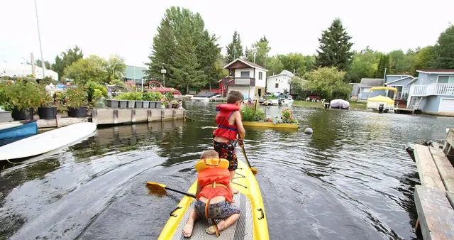Kids on a paddle board in the lakeside canal